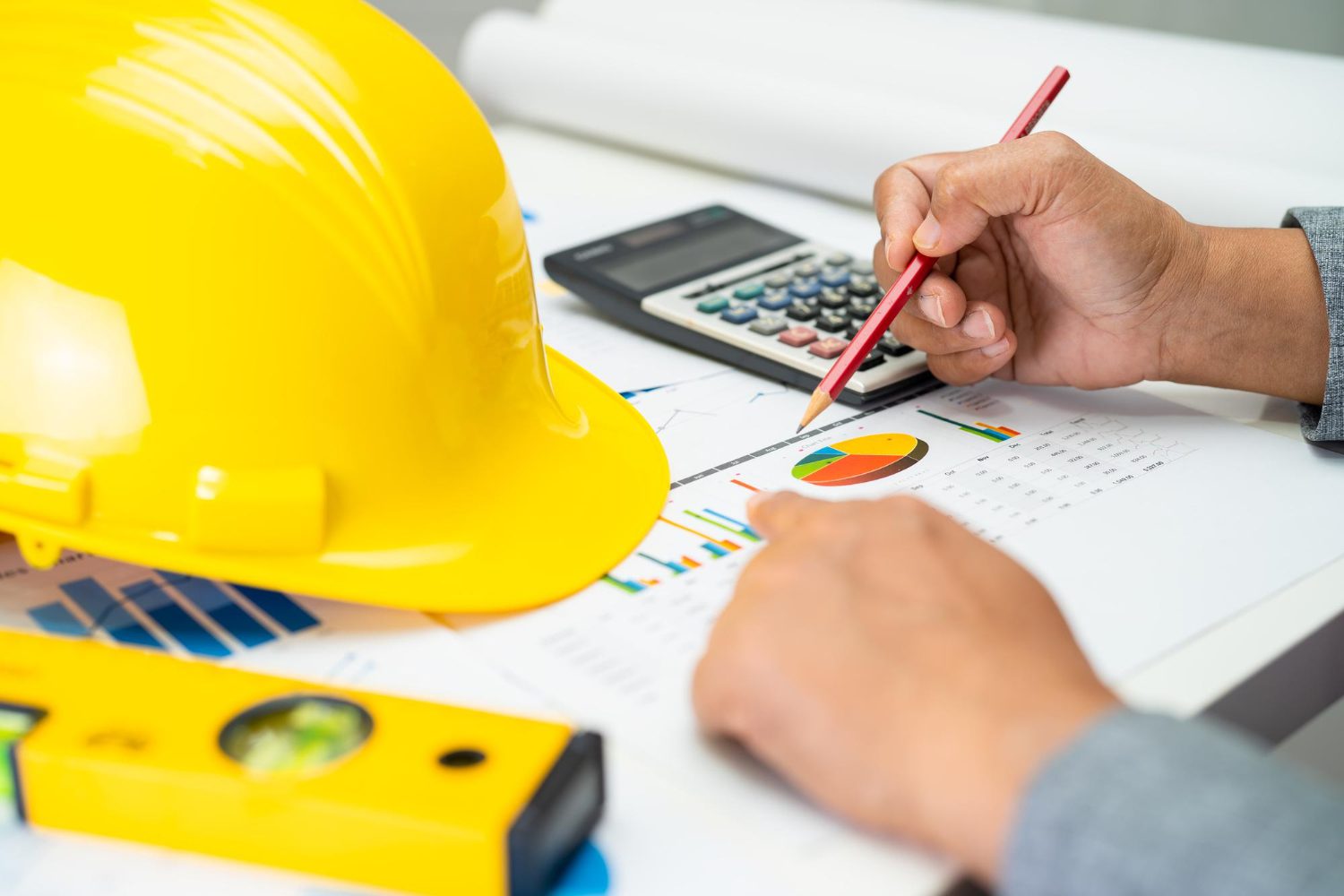 Asian engineer with architectural house plan project blueprint graph and yellow helmet and engineering construction tools
